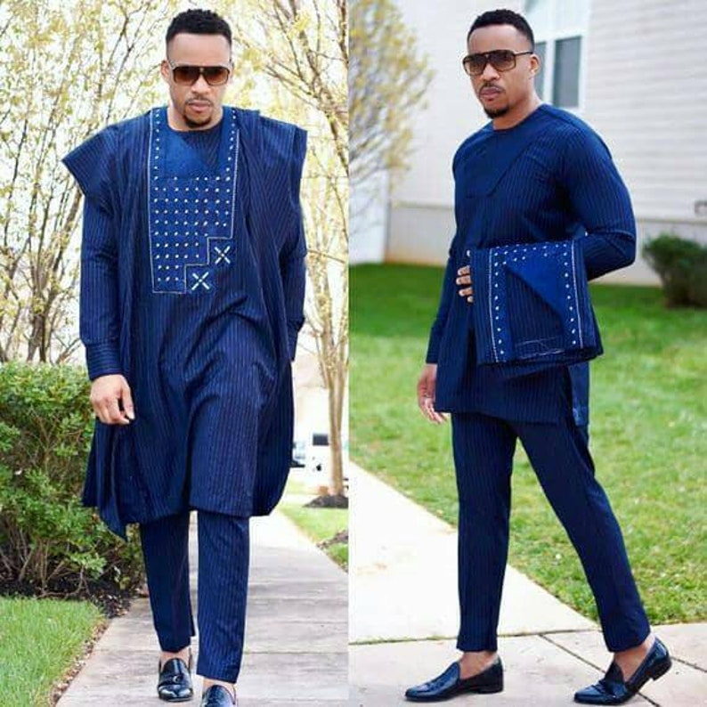 K&ouml;nnte beinhalten: Zwei M&auml;nner in passenden blauen Nadelstreifenanz&uuml;gen mit wei&szlig;en Akzenten. Die Outfits bestehen aus einem lang&auml;rmeligen Hemd und einer Hose. Beide M&auml;nner tragen Sonnenbrillen und schwarze Slipper.