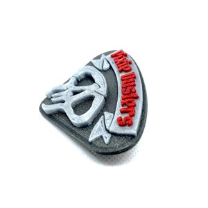 Puede incluir: Un parche impreso en 3D con un dise&ntilde;o de calavera y huesos cruzados. El texto "Grim Reapers" est&aacute; impreso en rojo sobre un fondo negro.