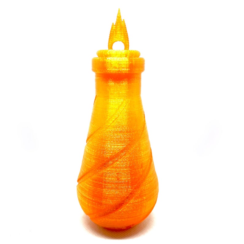 May include: A gold-colored, 3D printed bottle with a flame-shaped top. The bottle has a textured, swirling design.