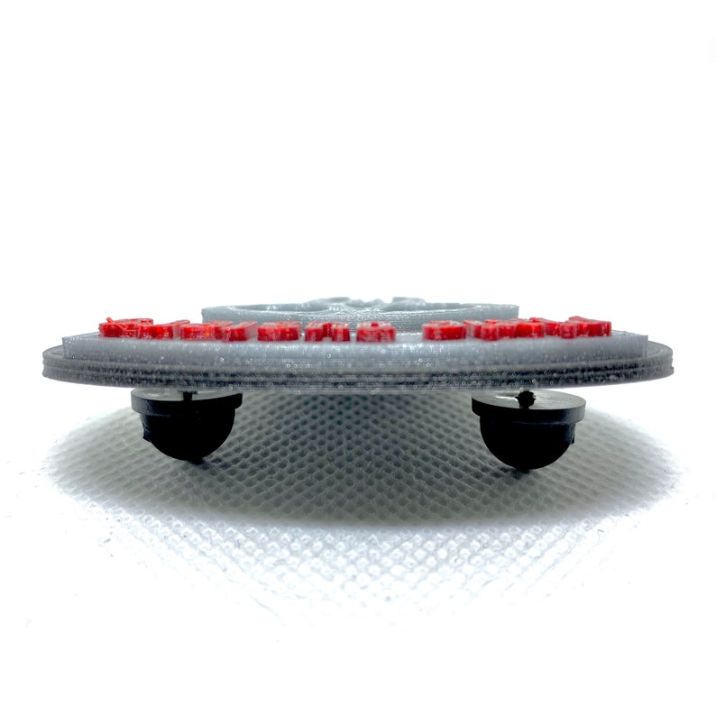 Puede incluir: Un pin gris impreso en 3D con letras rojas que dice "I'm With Stupid". El pin tiene dos postes de pl&aacute;stico negro en la parte posterior.