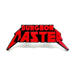 May include: A black and red metal pin with the text "Dungeon Master" in a stylized font.