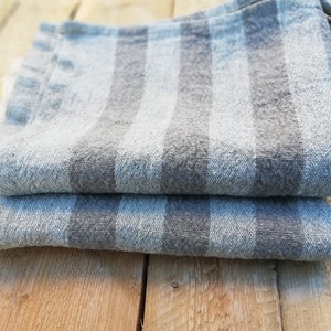 May include: Two gray and white striped kitchen towels folded on a wooden surface.