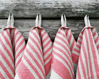 May include: Four red and white striped linen tea towels hanging on hooks against a weathered wooden background.