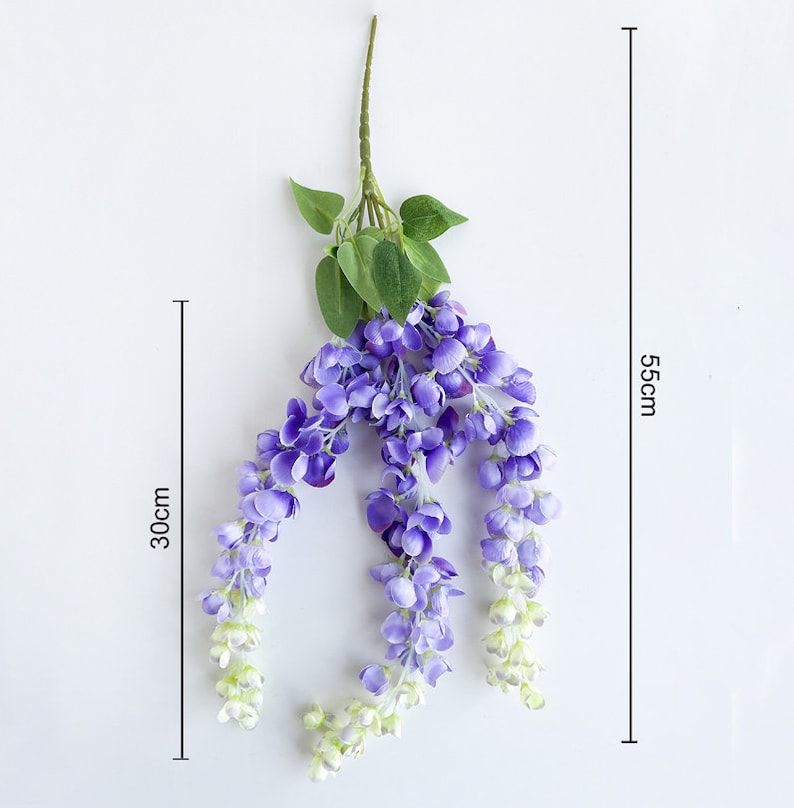 Pu&ograve; includere: Un lungo filo di fiori di glicine artificiali con fiori viola e foglie verdi. I fiori sono disposti a cascata e il filo &egrave; lungo circa 56 cm e largo 30 cm.