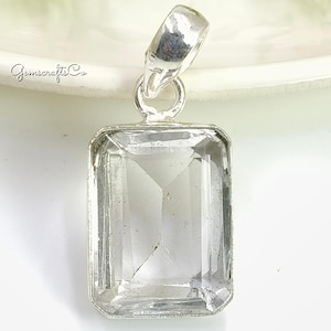 Könnte beinhalten: Rechteckiger, klarer Quarzanhänger mit silberfarbener Metalleinfassung. Der Quarz ist facettiert, und der Anhänger hat eine Schlaufe für eine Kette. Das Logo Gemscrafts Co. ist im Hintergrund sichtbar.
