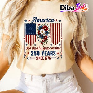 May include: A cream-coloured t-shirt with a patriotic design. The graphic features the American flag, floral elements, and the text: "America," "God shed his grace on thee," "250 YEARS," and "SINCE 1776."
