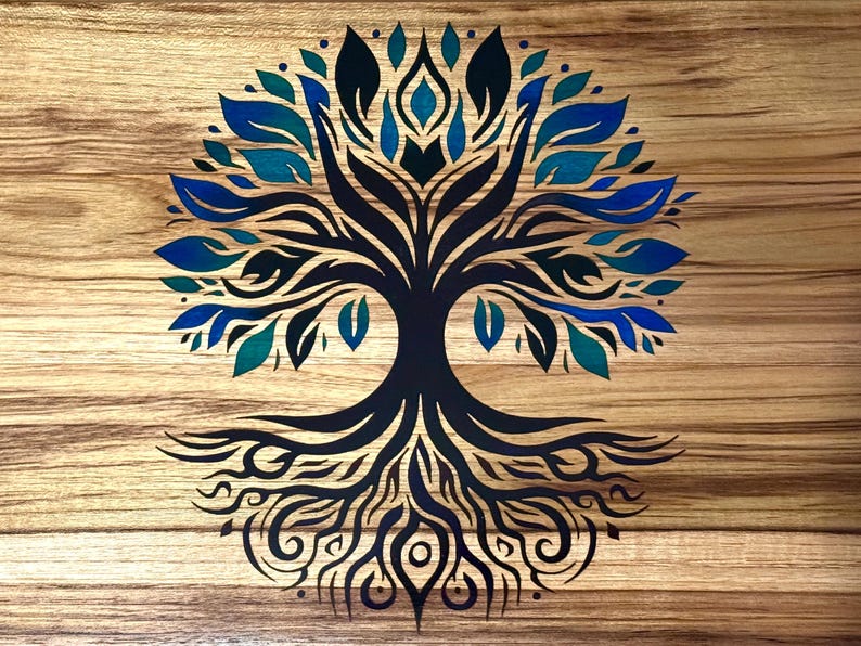 May include: A wooden artwork featuring a stylized tree design. The tree's trunk and roots are dark blue, with leaves in shades of blue and teal. The background is a light brown wood grain.