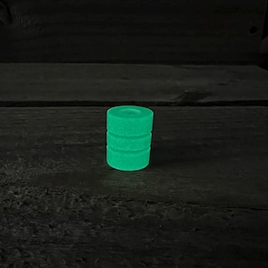 May include: A green glow-in-the-dark cylinder with a textured surface.