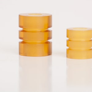 May include: Two amber-colored rubber bumpers, one larger than the other, with a ridged design. The bumpers are isolated on a white background.