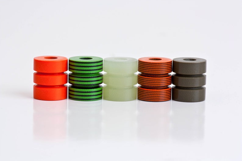 May include: Five stacked cylindrical beads in different colors and patterns. The beads are orange with black stripes, green with black stripes, white, orange with black stripes, and brown.