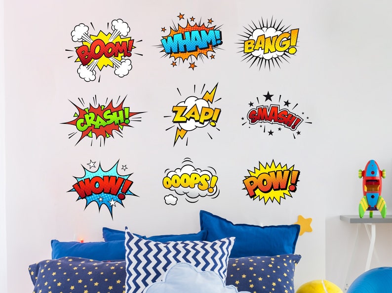 May include: A set of nine colorful comic book sound effect decals with words like "BOOM!" "WHAM!" "BANG!" "CRASH!" "ZAP!" "SMASH!" "WOW!" "OOPS!" and "POW!" The decals are on a white wall in a room with a bed and pillows.