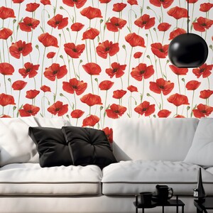 May include: White wallpaper with a repeating pattern of red poppy flowers. A white sofa with black cushions is in the foreground. A black pendant light hangs above the sofa.