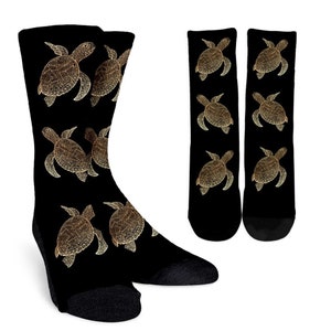 May include: A pair of black socks with a gold sea turtle design. The socks are crew length and have a ribbed cuff.