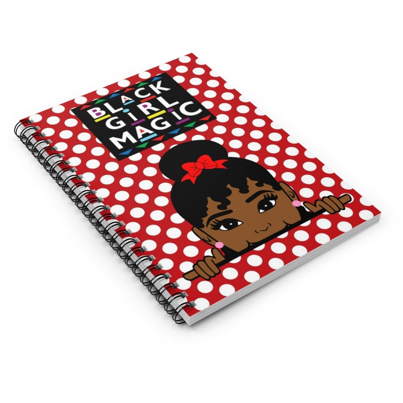 Peut inclure: Un carnet &agrave; spirales rouge avec des pois blancs. La couverture pr&eacute;sente une illustration de dessin anim&eacute; d'une fille noire avec un n&oelig;ud rouge dans les cheveux qui regarde par-dessus le bord du carnet. Le texte "BLACK GIRL MAGIC" est imprim&eacute; en lettres color&eacute;es sur un rectangle noir.