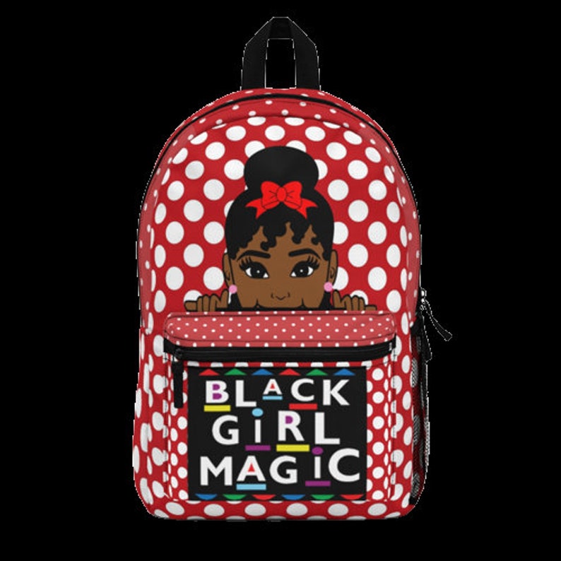 Peut inclure: Sac &agrave; dos rouge &agrave; pois blancs avec une illustration de dessin anim&eacute; d'une fille noire avec un n&oelig;ud rouge qui d&eacute;passe du haut de la poche. La poche porte le texte "BLACK GIRL MAGIC" en lettres color&eacute;es.