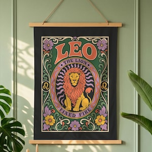 Peut inclure: Une tenture murale rectangulaire sur fond noir avec une illustration centrale de lion dans un cadre ovale. Le texte LEO, THE LION et FIXED FIRE est imprimé en orange et violet. Le motif comprend des fleurs vertes, jaunes et violettes.