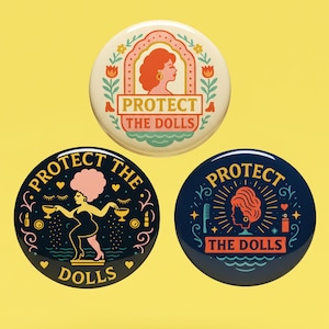 Puede incluir: Tres botones redondos con el texto "PROTECT THE DOLLS". El botón superior es de color crema con la silueta de una mujer pelirroja. El botón inferior izquierdo es negro con una mujer sosteniendo bebidas. El botón inferior derecho es azul marino con una silueta de mujer.