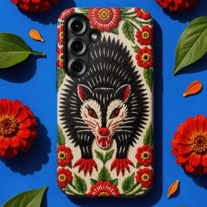 May include: A phone case featuring a textured, embroidered-style illustration of a black and white opossum with red eyes, nose, and claws. The design is surrounded by vibrant red flowers with yellow centres and green leaves on a cream background.