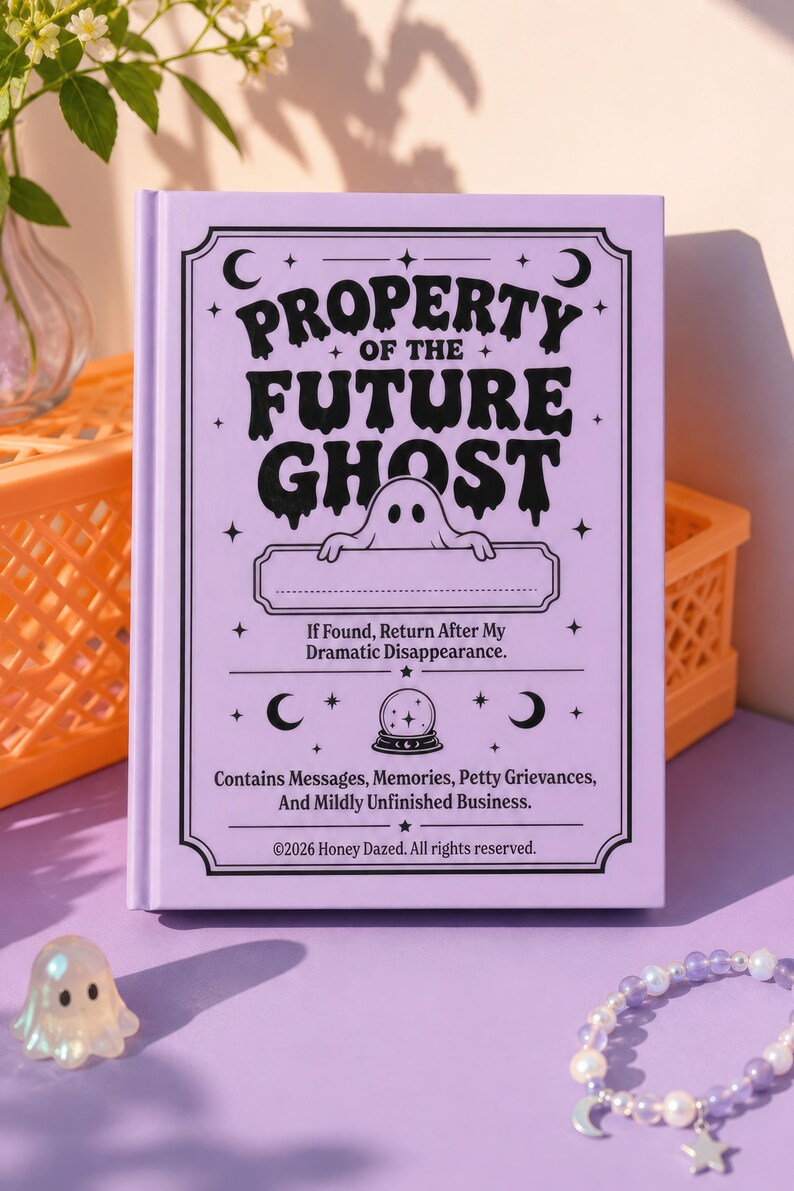 A 5 by 7 inch hardcover journal with a matte pastel purple cover and black printed graphics. The front features a retro inspired illustration of a white ghost character. One design shows the ghost holding a locked book flanked by a lit candle and a skeleton key with text reading Notes For My Future Ghost. The other shows the ghost peeking over a blank label with text reading Property Of The Future Ghost. Both include crescent moons, four point stars, and vintage decorative border frames.