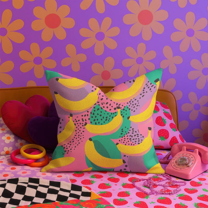 Square pillowcase featuring a bold and playful banana print in a vibrant pop art style. The design includes bright yellow bananas layered over a backdrop of pink, purple, green, and teal with dotted and speckled textures for a dynamic, retro-inspired look. Made of smooth fabric with crisp edges and a snug fit, the pillowcase showcases a saturated, high-contrast palette perfect for maximalist or dopamine decor. Pillow cover only; insert not included.