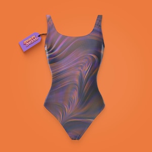 May include: A one-piece swimsuit featuring a scoop neckline and a dark, swirling abstract pattern in shades of purple, blue, and orange. A purple rectangular tag attached to the shoulder displays the text Honey Dazed in orange lettering.