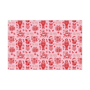 Premium satin finish wrapping paper featuring a repeating pastel goth pattern on a pink background. The design showcases a playful yet spooky aesthetic with high-contrast skeleton nutcrackers, skull jack-in-the-boxes, and rocking horse skeletons in soft pinks, and reds. The paper texture appears semi-glossy. Shown in three available sizes including sheets and rolls, specifically 29 inches wide, suitable for wrapping gifts for holidays, birthdays, or gothic themed occasions.