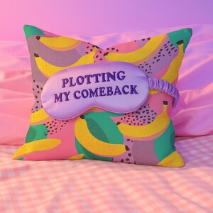 Square pillowcase featuring a bold and playful banana print in a vibrant pop art style. The design includes bright yellow bananas layered over a backdrop of pink, purple, green, and teal with dotted and speckled textures for a dynamic, retro-inspired look. Made of smooth fabric with crisp edges and a snug fit, the pillowcase showcases a saturated, high-contrast palette perfect for maximalist or dopamine decor. Pillow cover only; insert not included.