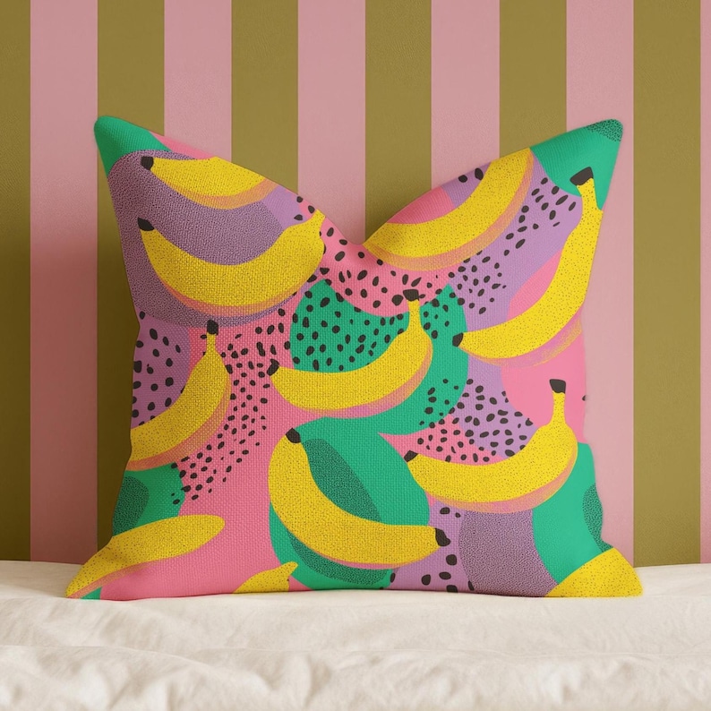 Square pillowcase featuring a bold and playful banana print in a vibrant pop art style. The design includes bright yellow bananas layered over a backdrop of pink, purple, green, and teal with dotted and speckled textures for a dynamic, retro-inspired look. Made of smooth fabric with crisp edges and a snug fit, the pillowcase showcases a saturated, high-contrast palette perfect for maximalist or dopamine decor. Pillow cover only; insert not included.