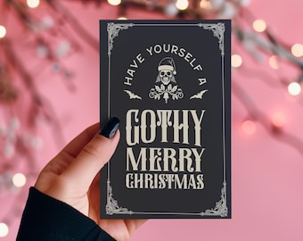 Könnte beinhalten: Eine schwarze Karte mit weißem Rand und weißem Text, der "Have yourself a Gothy Merry Christmas" lautet. Über dem Text befindet sich ein Schädel, der einen Weihnachtsmann-Hut trägt. Die Karte wird von einer Hand mit schwarzem Nagellack gehalten.