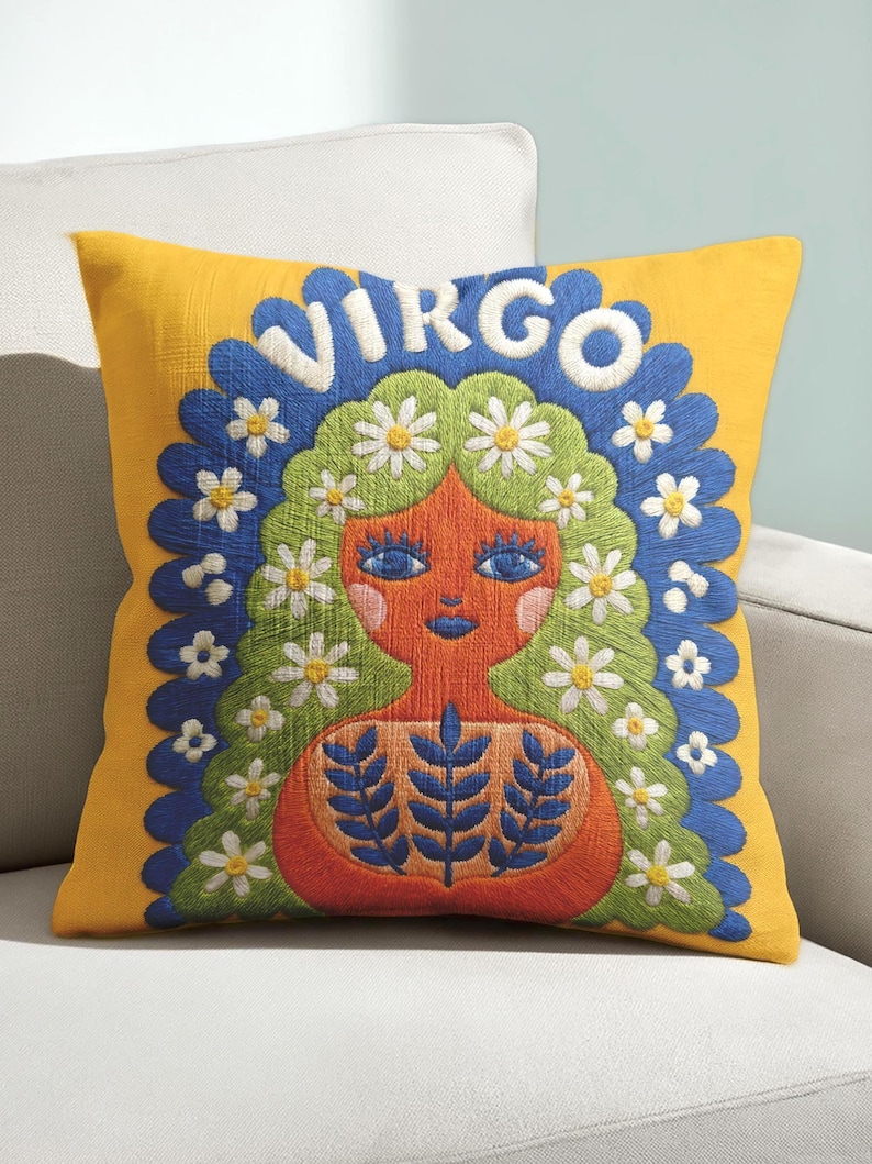 A square throw pillow featuring a vibrant Virgo zodiac design on a golden mustard yellow background. The central illustration shows a terracotta-skinned figure with green hair adorned with white daisies. Blue leaf motifs are printed on the figure’s chest. The word "VIRGO" appears in white bubble letters at the top. The entire design is framed by a royal blue scalloped border, featuring a high-fidelity trompe-l'œil print that mimics 3D embroidery.