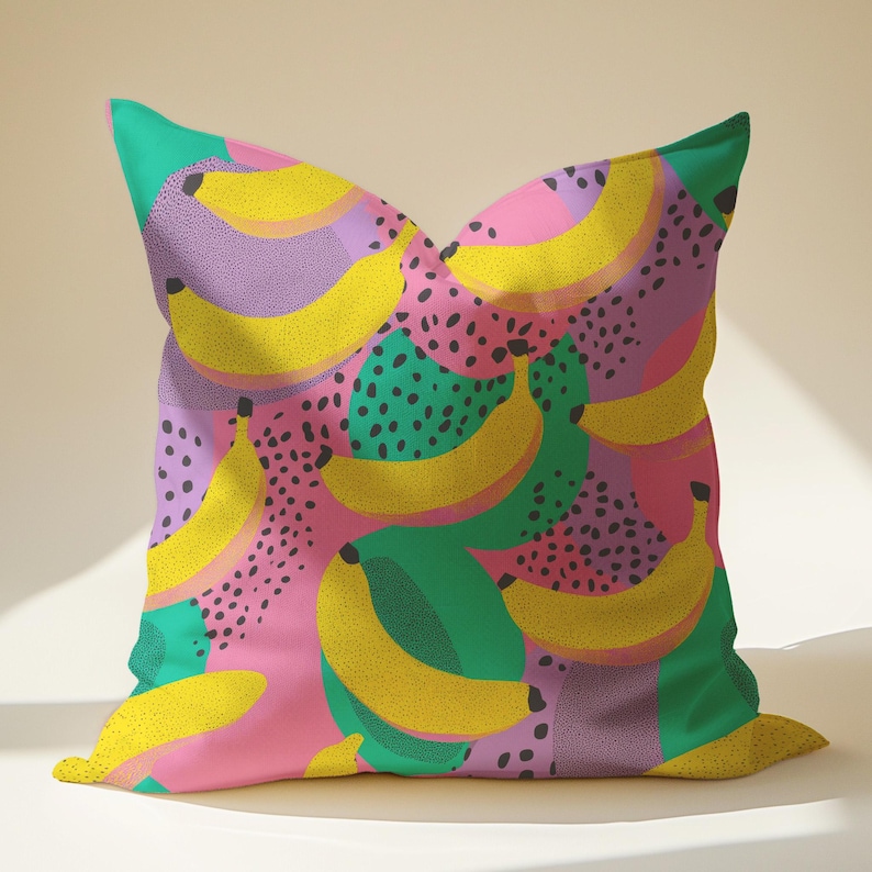 Square pillowcase featuring a bold and playful banana print in a vibrant pop art style. The design includes bright yellow bananas layered over a backdrop of pink, purple, green, and teal with dotted and speckled textures for a dynamic, retro-inspired look. Made of smooth fabric with crisp edges and a snug fit, the pillowcase showcases a saturated, high-contrast palette perfect for maximalist or dopamine decor. Pillow cover only; insert not included.