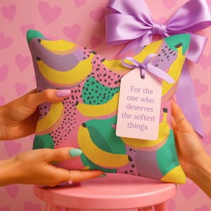 Square pillowcase featuring a bold and playful banana print in a vibrant pop art style. The design includes bright yellow bananas layered over a backdrop of pink, purple, green, and teal with dotted and speckled textures for a dynamic, retro-inspired look. Made of smooth fabric with crisp edges and a snug fit, the pillowcase showcases a saturated, high-contrast palette perfect for maximalist or dopamine decor. Pillow cover only; insert not included.