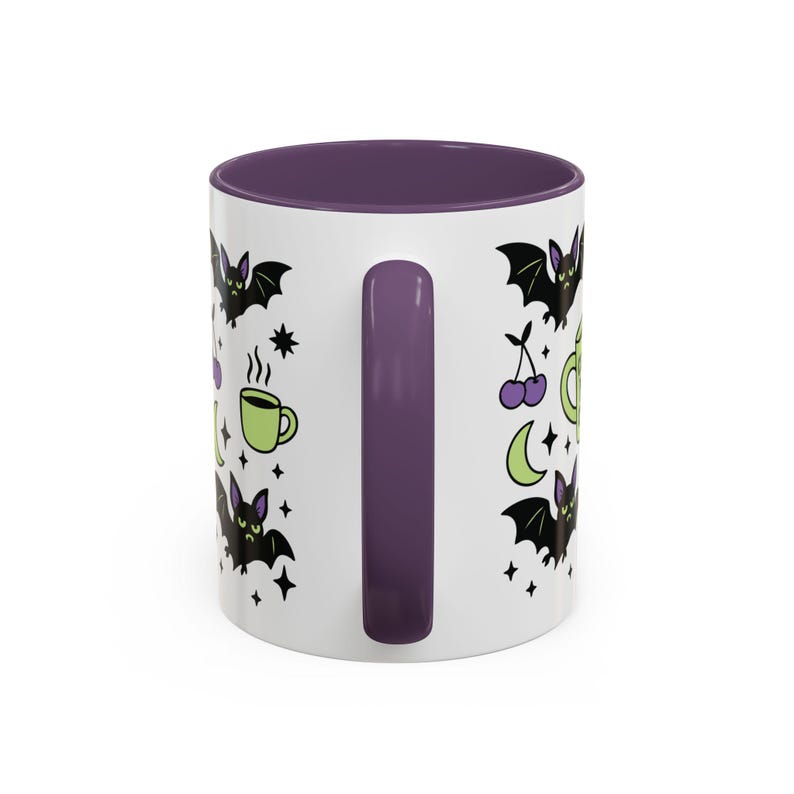 White ceramic mug with vibrant purple interior and matching C-handle. Features a full wrap-around, 'spooky cute' pastel goth design. Central graphic is a lime green coffee cup with 'CERTIFIED NIGHT CREATURE' in black text. Surrounding illustrations include grumpy black bats, a steaming green coffee cup, a purple mug, vampire fangs, crescent moon, black cherries, and an alarm clock. Design uses bold graphics in black, lime green, and purple, accented with small black stars. Pastel Goth vibes.