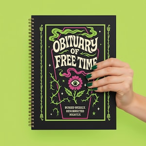May include: A black spiral-bound notebook with the words "Obituary of Free Time" in white and green lettering. The cover features a pink flower with an eye and the text "Buried Weekly. Resurrected Nightly." The background is a bright green.