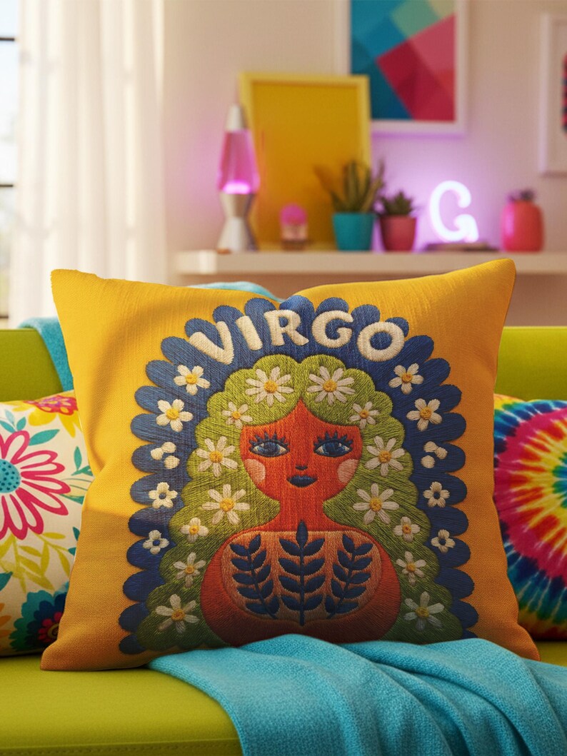 A square throw pillow featuring a vibrant Virgo zodiac design on a golden mustard yellow background. The central illustration shows a terracotta-skinned figure with green hair adorned with white daisies. Blue leaf motifs are printed on the figure’s chest. The word "VIRGO" appears in white bubble letters at the top. The entire design is framed by a royal blue scalloped border, featuring a high-fidelity trompe-l'œil print that mimics 3D embroidery.