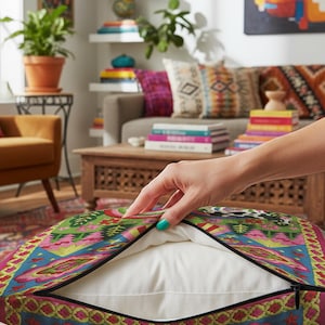 Description of a square throw pillow with a vibrant maximalist alien design. A central UFO with a large all-seeing eye hovers above a landscape with two rainbows, pink mountains, and green pine trees. A black and white spotted cow stands in the foreground. The design is a high-contrast palette of sky blue, magenta, hot pink, and meadow green. The pillow has a faux-embroidery 2D print finish on linen-feel fabric, framed by a yellow and pink scalloped floral border.