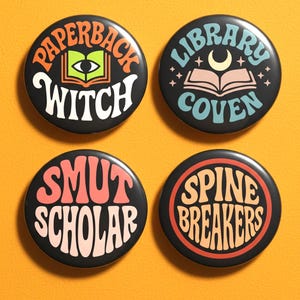 May include: Four black round buttons with text and graphics. The buttons say "Paperback Witch", "Library Coven", "Smut Scholar", and "Spine Breakers". The buttons are on an orange background.