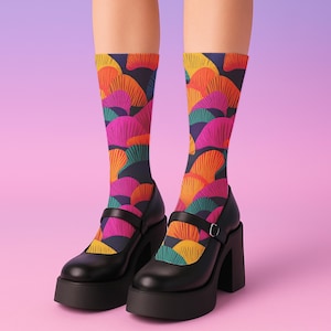 Puede incluir: Zapatos Mary Jane negros con plataforma, con correa y hebilla, combinados con calcetines hasta la rodilla. Los calcetines presentan un colorido estampado de abanicos en tonos naranja, rosa, turquesa y amarillo sobre un fondo azul oscuro.