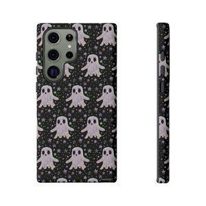 Black phone case featuring white textured ghost pattern with multicolored star accents. Kawaii-style ghosts with simple black eyes on dark background.