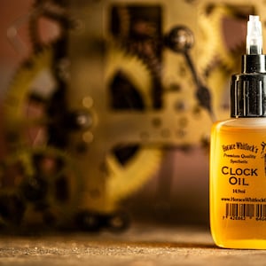 May include: A small bottle of Horace Whitlock's Clock Oil, a premium quality synthetic oil for clocks. The bottle is clear and has a black cap with a dropper. The label is white with black text and features a small illustration of a man in a top hat. The text on the label reads "Horace Whitlock's Premium Quality Synthetic CLOCK OIL 14ml www.HoraceWhitlockOil.com".
