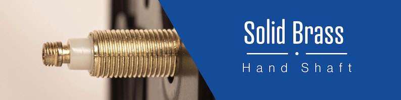 May include: Close-up of a gold-colored solid brass hand shaft. The shaft has a threaded end and a white plastic piece.