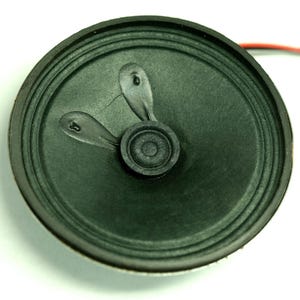 May include: A black round speaker with a green cone and two small black tabs on the cone.