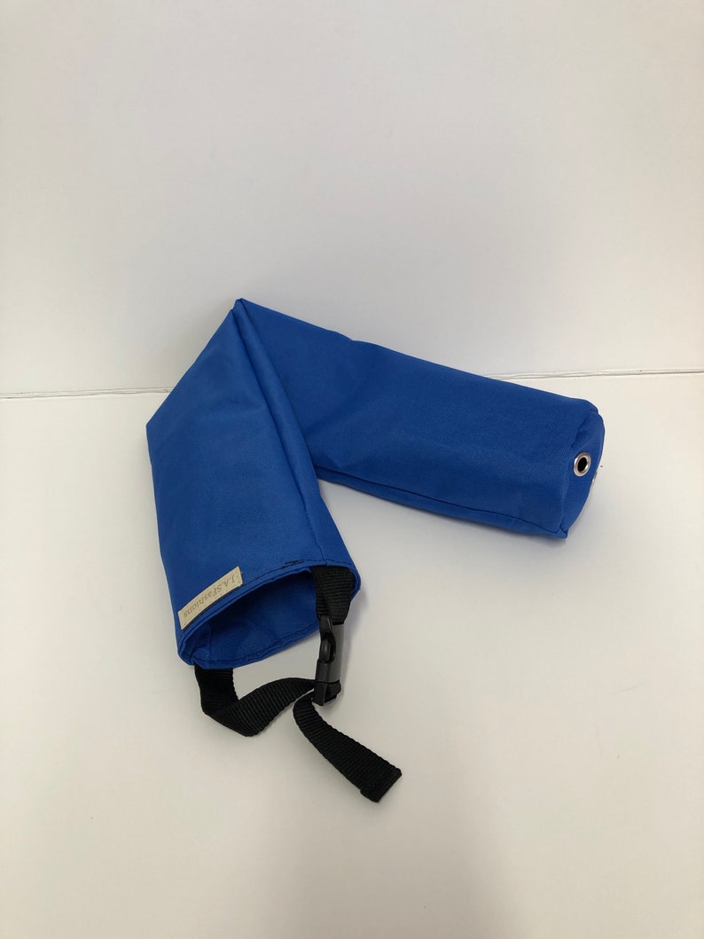 Pu&ograve; includere: Un tubo in tessuto blu brillante dal design piegato, dotato di una cinghia in nylon nero con fibbia in plastica, un occhiello metallico argentato a un'estremit&agrave; e una piccola etichetta rettangolare beige con la scritta J.A.Fashions sul lato.