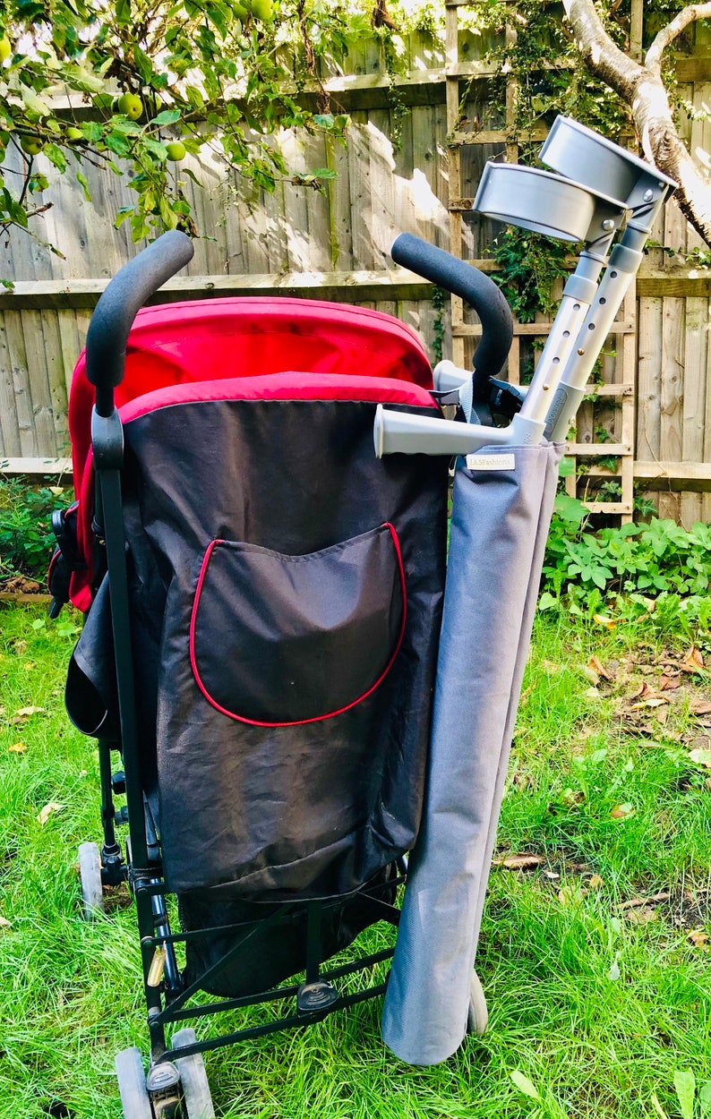 Pu&ograve; includere: Un passeggino rosso e nero con una tasca portaoggetti nera con bordo rosso. Un supporto in tessuto grigio per stampelle &egrave; fissato lateralmente, contenente un paio di stampelle antibrachiali grigie con impugnature e bracciali neri. Etichetta.