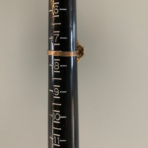 May include: A gold ring with a floral design and a single, clear stone. The ring is shown on a ruler, measuring approximately 8 inches in diameter.
