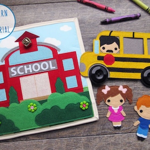 Op de afbeelding: Een vilt speelset voor kinderen met een rood schoolgebouw met het woord "SCHOOL" op de voorkant, een gele schoolbus met een chauffeur en twee vilt figuren van kinderen.