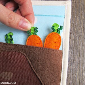 May include: A felt play set with a brown patch of felt representing dirt.  There are three green felt carrot tops and two orange felt carrots.  The carrots are attached with velcro and can be removed.