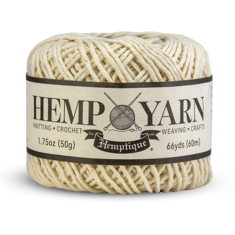 K&ouml;nnte beinhalten: Ein Kn&auml;uel naturfarbenes Hanfgarn mit einem schwarz-cremefarbenen Etikett. Das Etikett tr&auml;gt die Aufschrift "HEMP YARN" mit "KNITTING CROCHET" und "WEAVING CRAFTS" darunter. Es wiegt 50g und ist 60m lang.