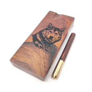 May include: A wooden box with a wolf design and a wooden and brass poker tool. The box is brown with a dark wood grain and the wolf is black.