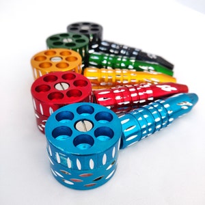 May include: A collection of colorful, metallic smoking pipes in various colors, including blue, red, yellow, green, and black. Each pipe features a cylindrical chamber with multiple holes and a matching stem.